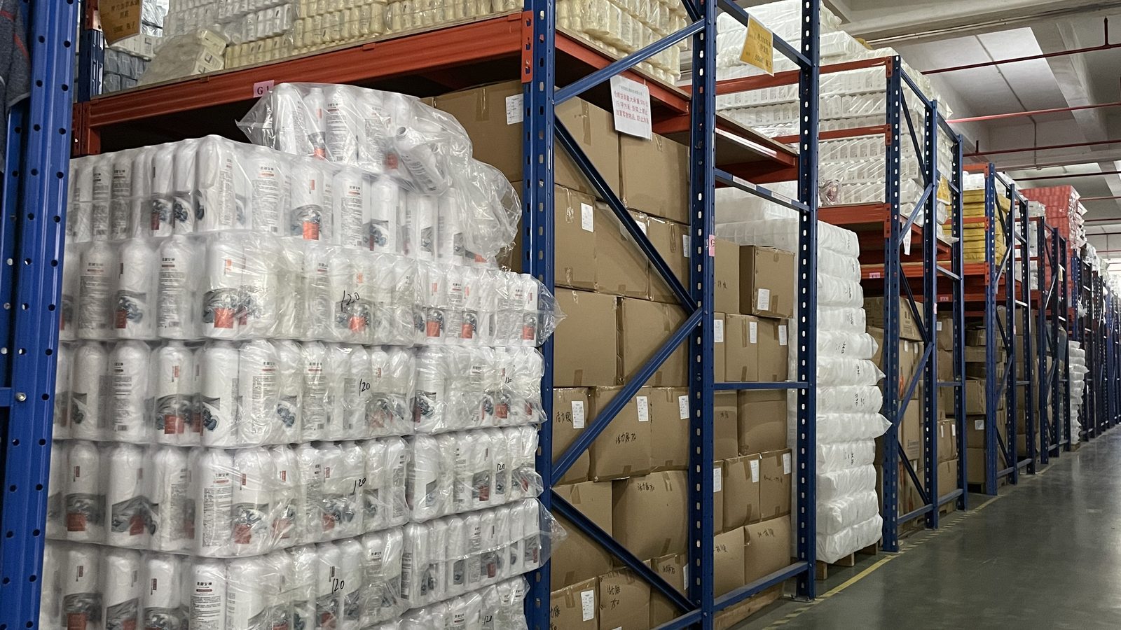 Warehouse racks stacked with shrink-wrapped packs of shampoo bottles