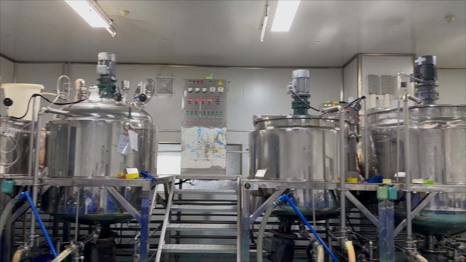 Stainless steel mixing tanks on the production floor of a shampoo OEM factory